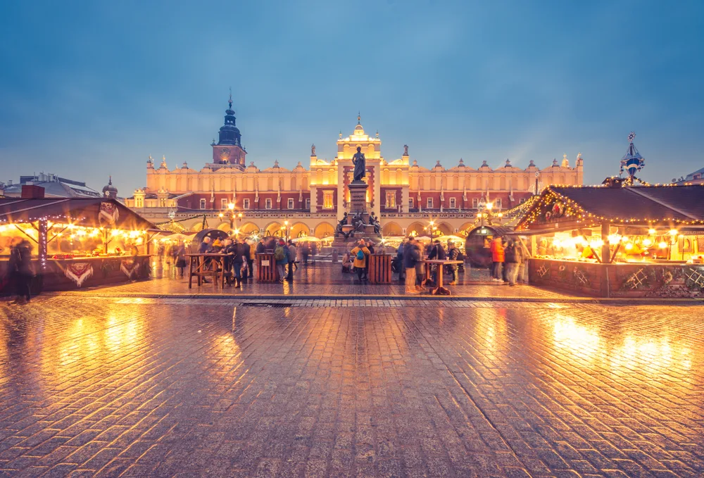 Main town square in Krakow pictured with snow on the ground and gloomy skies during the cheapest time to visit Poland