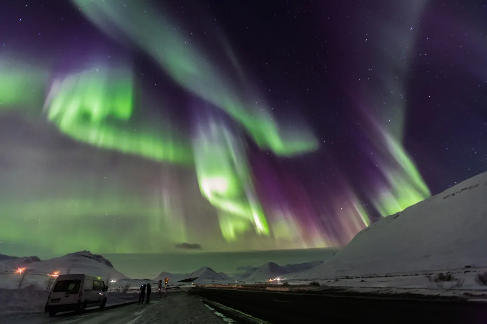 Northern Lights pictured high above the snow-capped hills during the best time to visit Anchorage Alaska