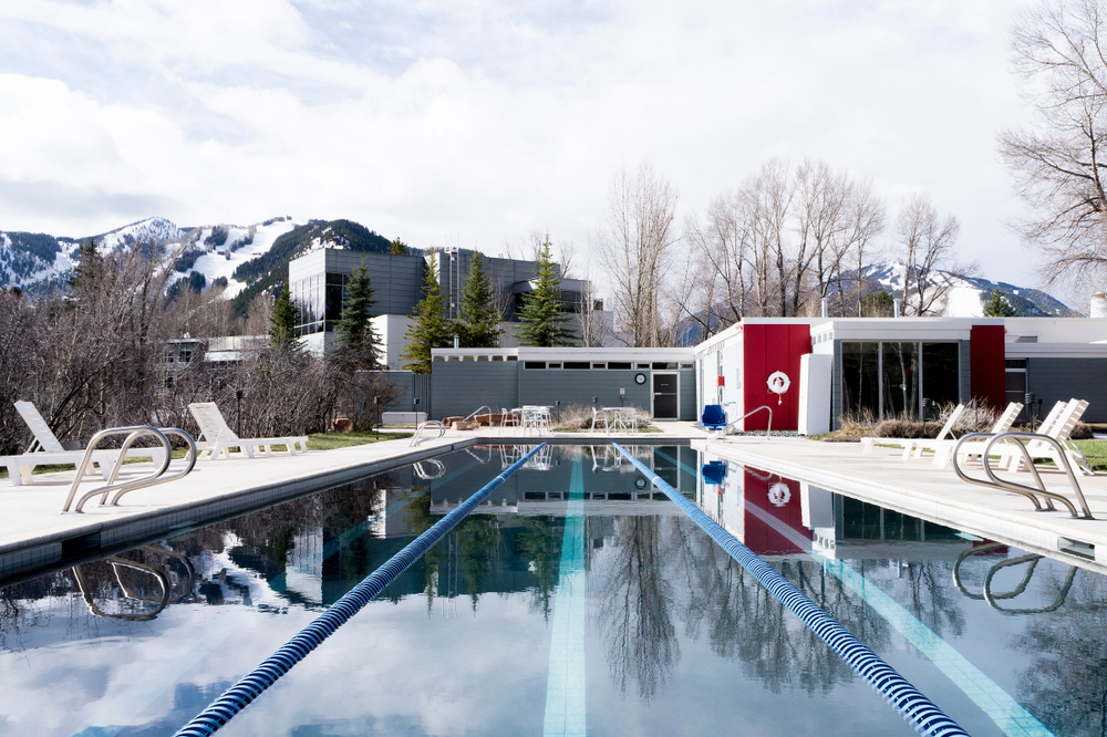 Gorgeous mountain view of a resort with a lap pool outside during the cheapest time to visit Aspen