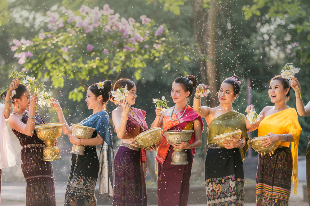 Woman in sarees splashing each other during Songkran, the Thai new year, during the cheapest time to visit Bangkok