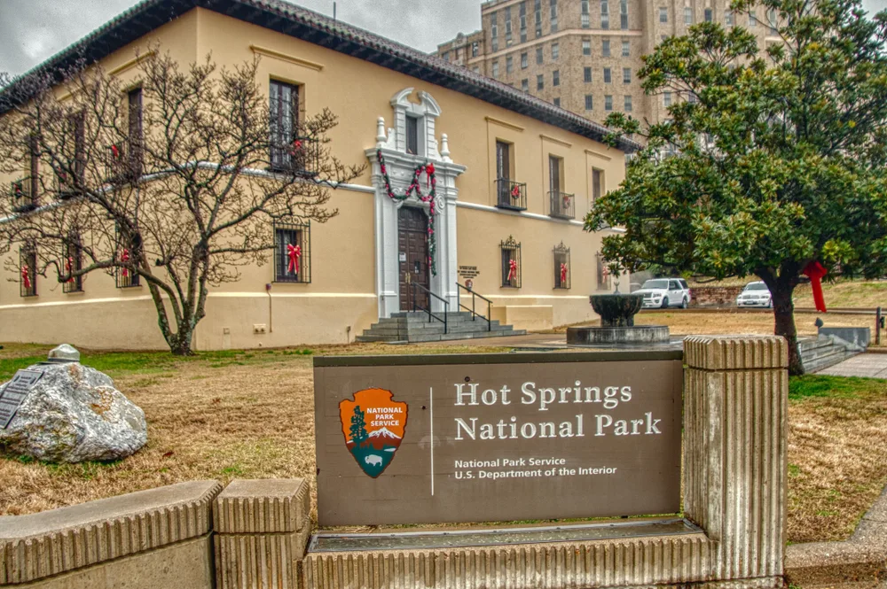 Hot Springs National Park sign during the winter with red bows decorating the building during the cheapest time to visit Hot Springs Arkansas
