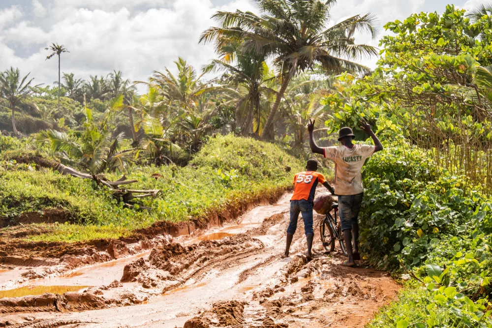 Two kids on a dirt road when it's raining during the worst time to visit Ghana, the wet season
