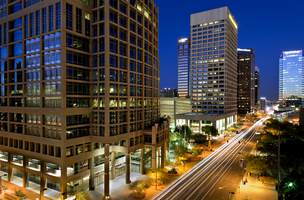 Long exposure image of downtown Phoenix at night with cars driving by and big buildings towering over the street during the best time to visit Phoenix