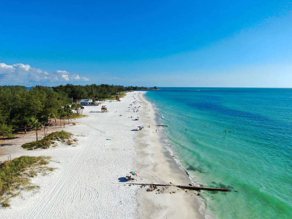 Aerial view of the island with people scattered on the beach in summer during the worst time to visit Anna Maria Island