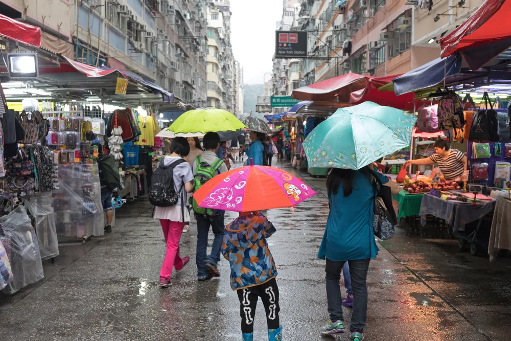People in an open-air market during monsoon season, the cheapest time to visit Hong Kong