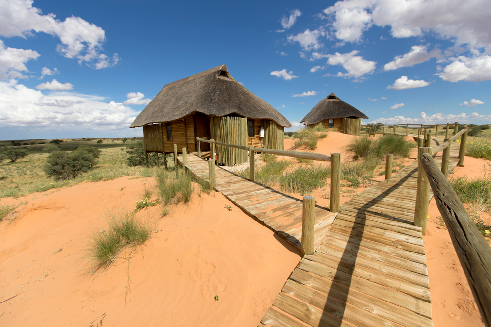 Lodge with traditional stick and wood huts with a big wooden walkway spanning the desert during the least busy time to visit Botswana