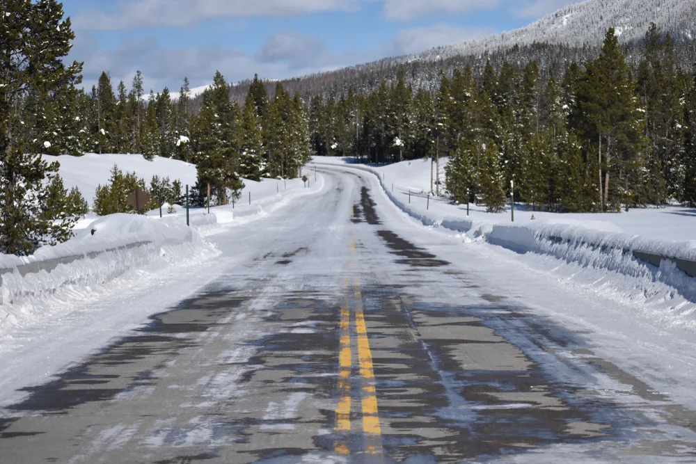 Snow-covered road pictured from the perspective of a driver for a piece on the worst time to visit Wyoming
