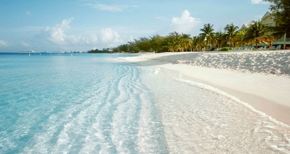 Gorgeous white sand of Seven Mile Beach beach lining teal and clear water, pictured during the best time to visit the Cayman Islands