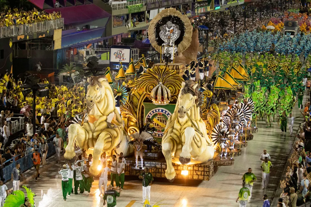 Nighttime view of the massive Carnaval parade with crowds lining the streets as people walk alongside an elephant float during the best time to visit Rio de Janeiro