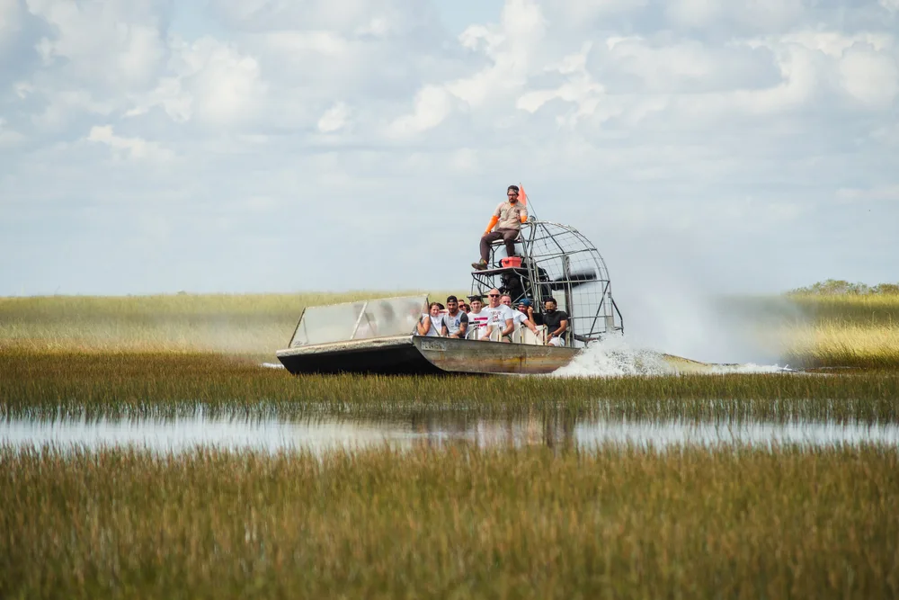 People take an airboat ride through the swamps to show the worst time to visit the Everglades