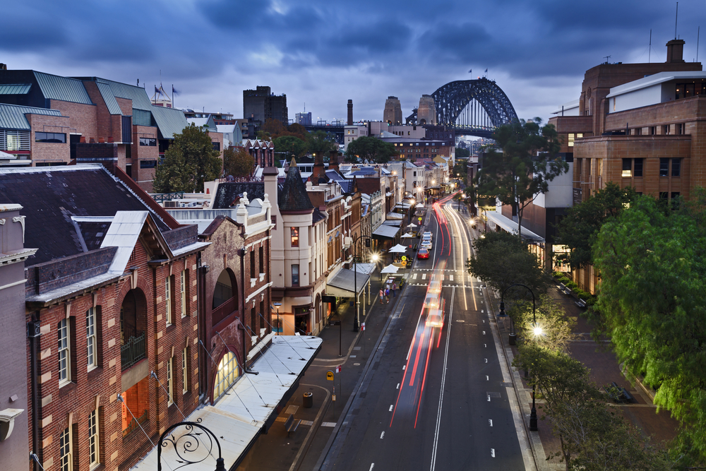 View from the rooftop of a large brick building in Sydney overlooking a busy street and providing a view out toward the bridge