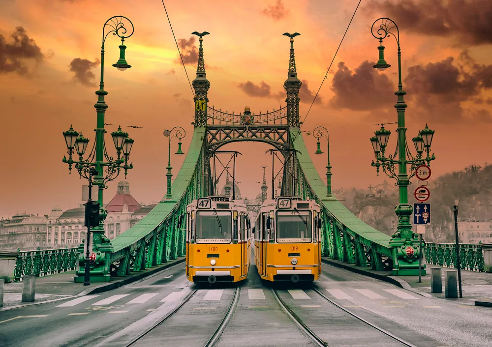 Two yellow trams on Liberty Bridge at sunset during the best time to visit the capital Budapest