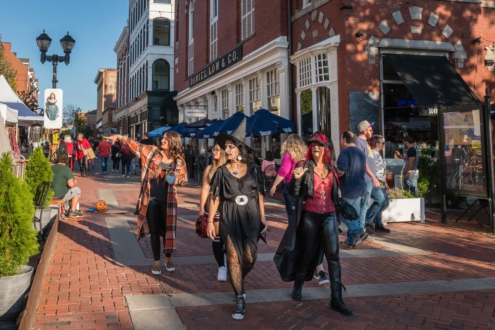 Women dressed in witch costumes pictured walking down the street for a piece on the best time to visit Salem, MA