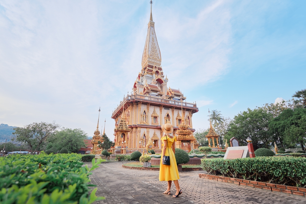 Young woman in a yellow dress touring a temple during the least busy time to visit Phuket