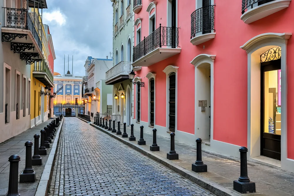 Gorgeous view of the old street in San Juan with pink buildings on either side of the brick road, pictured during the least busy time to visit Puerto Rico