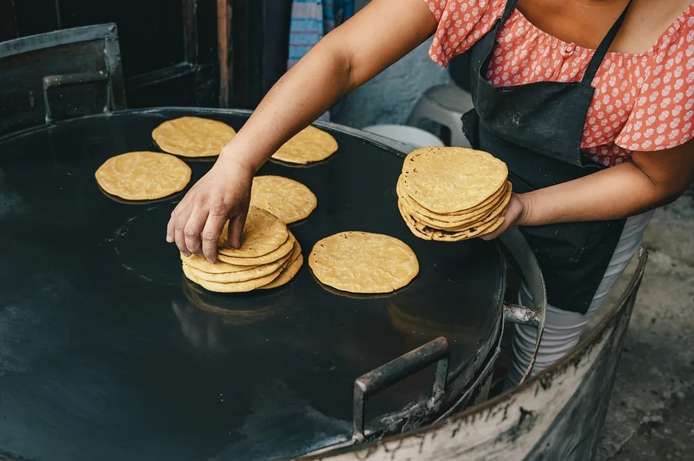Faceless Guatemalan woman preparing fresh tortillas on a big black cast iron stove