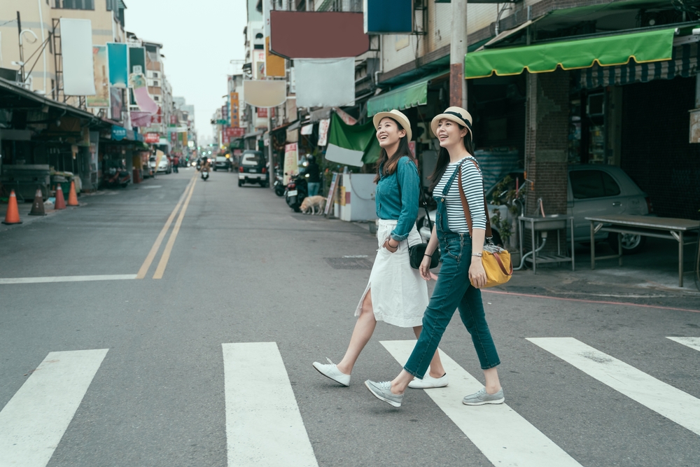 Two women walking on a path across a market street during the best time to visit Taiwan