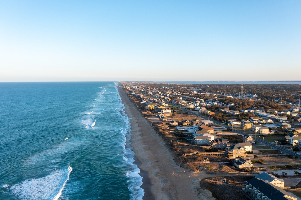 Serene coastline in the Outer Banks during the best time to visit with hardly anyone on the beach, as seen from an aerial POV