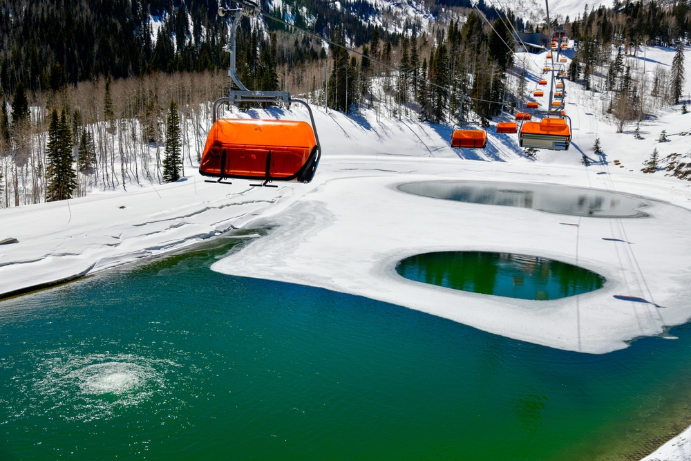 Orange ski lift chairs over melting ice on a pond in Park City Canyons Ski Area during the worst time to visit Park City Utah