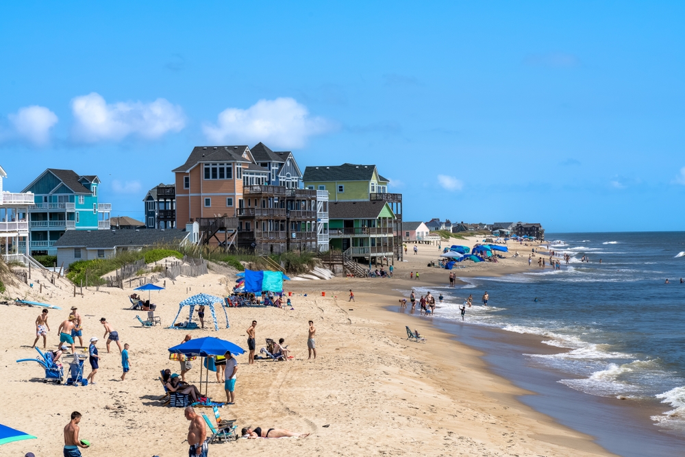 Photo of a crowded beach in the Outer Banks, taken during the summer, the worst time to visit with lots of people and umbrellas and chairs scattered about