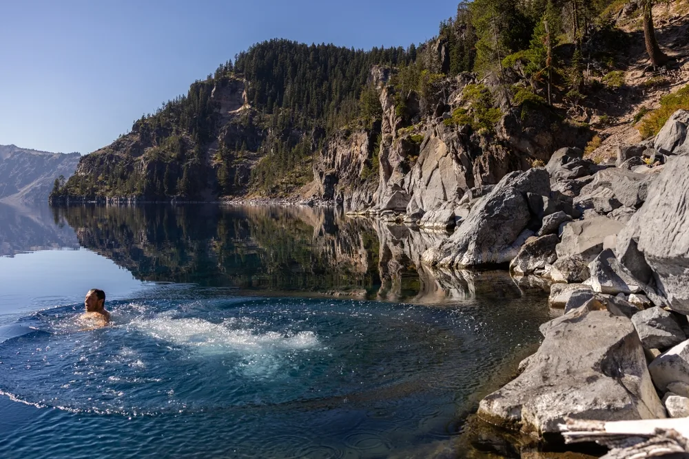 Man swimming in Crater Lake after hiking down the Cleetwood Cove Trail