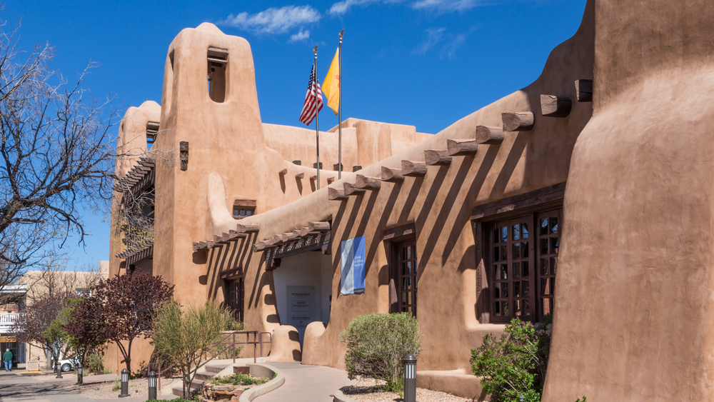 Photo of the exterior of the New Mexico Museum of Art pictured in front of a blue sky during the least busy time to visit Santa Fe