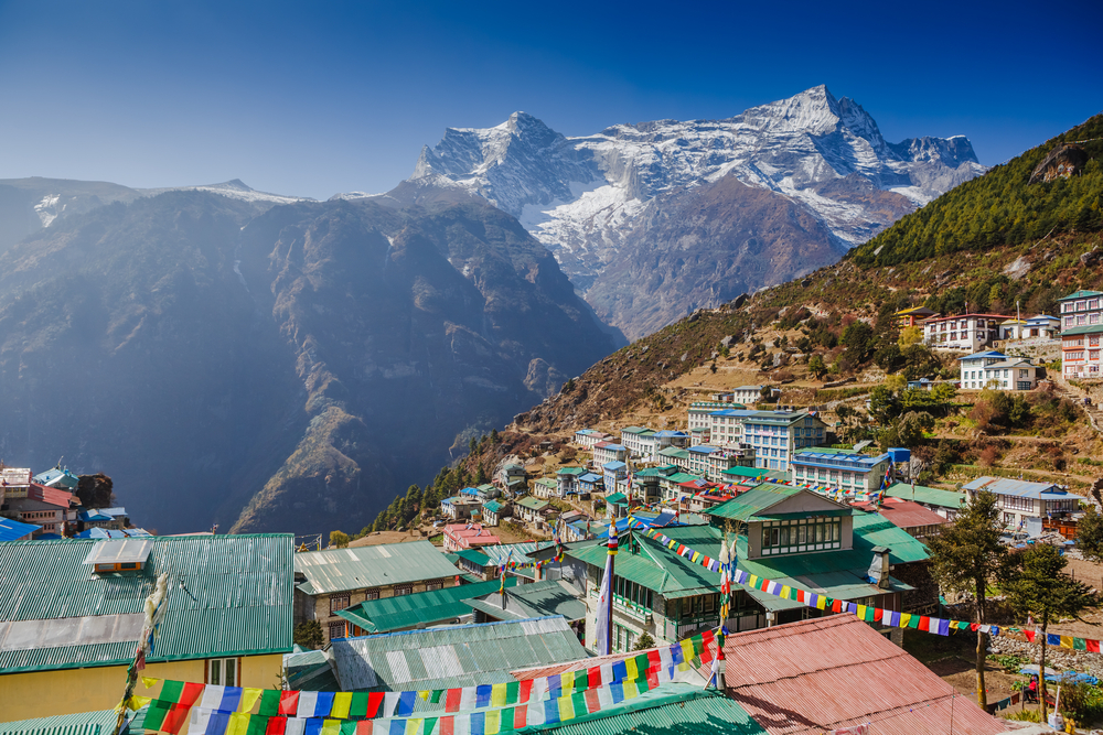 Aerial view from a hilltop of the Namche Bazar in Khumbu with a postcard-worthy view of the snow-capped Himalayas and the deep valley below