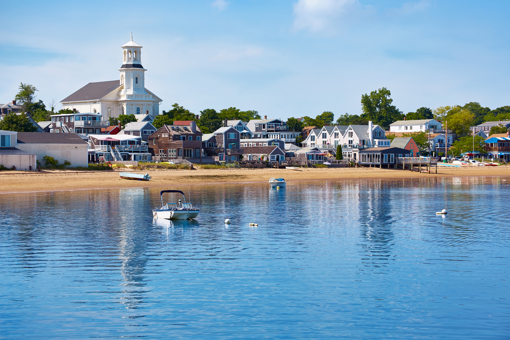 Provincetown beach in Cape Cod pictured during the summer, the best time to go, with boats on the water in front of picturesque homes