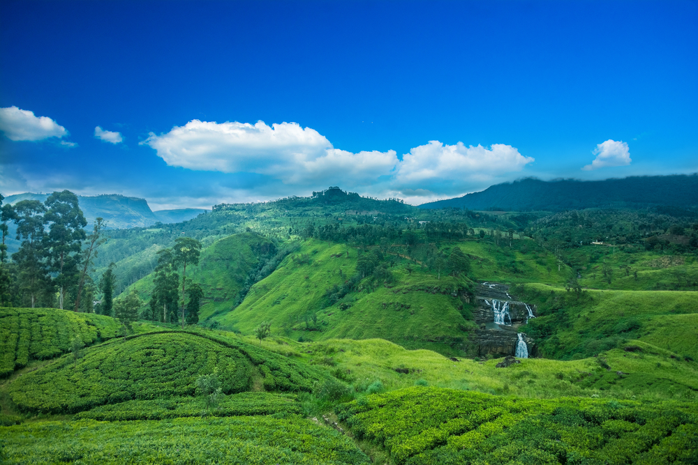 Amazing view of the St. Clairs waterfall and landscape with blue skies and green grass during the best time to visit Sri Lanka
