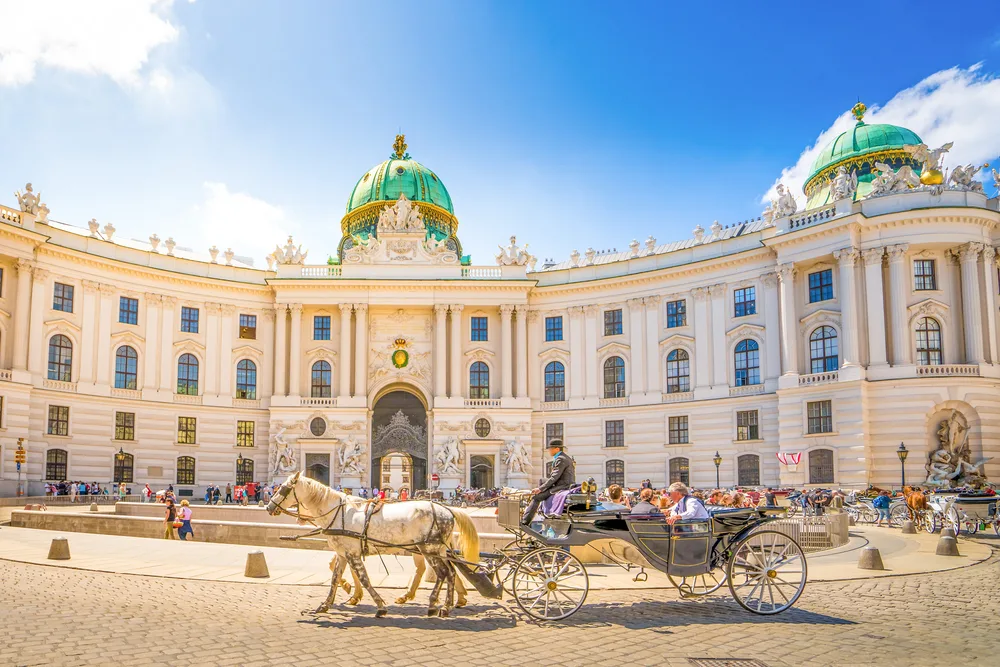 Alte Hofburg on a sunny day with horse drawn carriage during the best time to visit Vienna