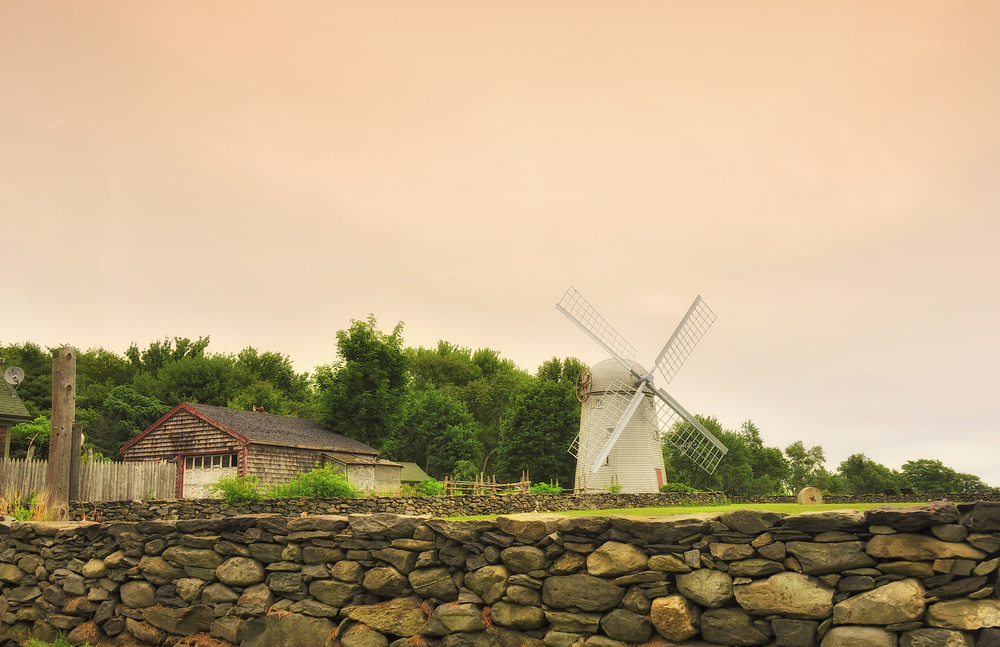 Farm with windmill and stone wall on a cloudy day showing the best time to visit Rhode Island