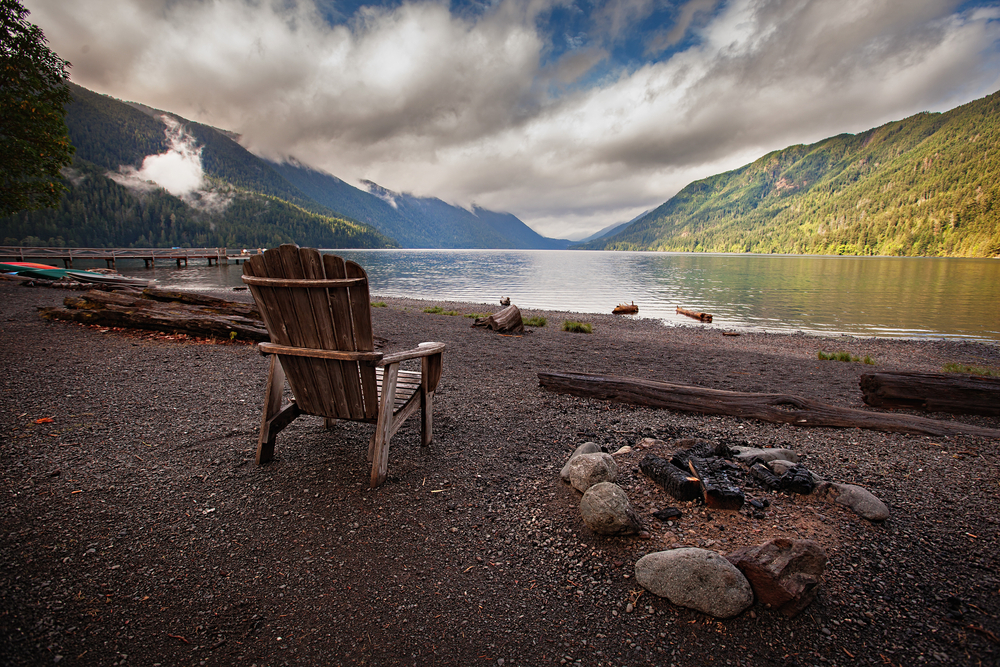 Empty wooden chair on the black sand beach of Lake Crescent in Washington State pictured during the least busy time to visit
