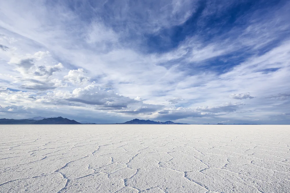 Wide angle view showing the worst time to visit the Bonneville Salt Flats with blue skies and clouds overhead