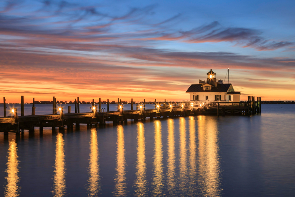 An amazingly gorgeous photo of a lighthouse on a pier during the best time to visit the Outer Banks
