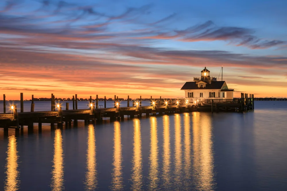 An amazingly gorgeous photo of a lighthouse on a pier during the best time to visit the Outer Banks