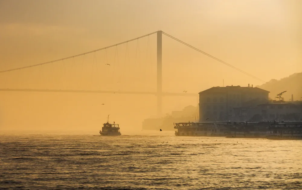 Boat on the water seen through some very thick fog with a brown sky during the worst time to visit Istanbul
