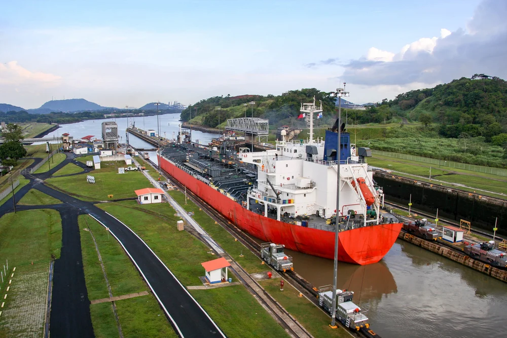Big ship cruising through the canal during the best time to visit Panama, with green grass and warm weather