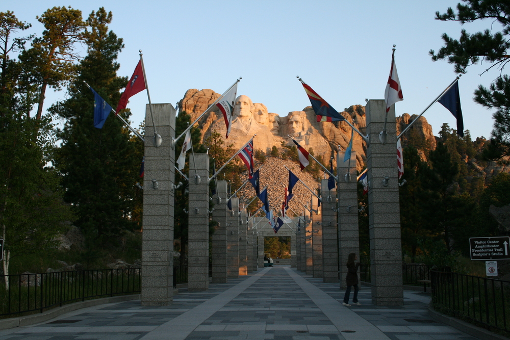Cool path heading towards Mount Rushmore in the fall pictured during the least busy time to visit South Dakota with flags on either side