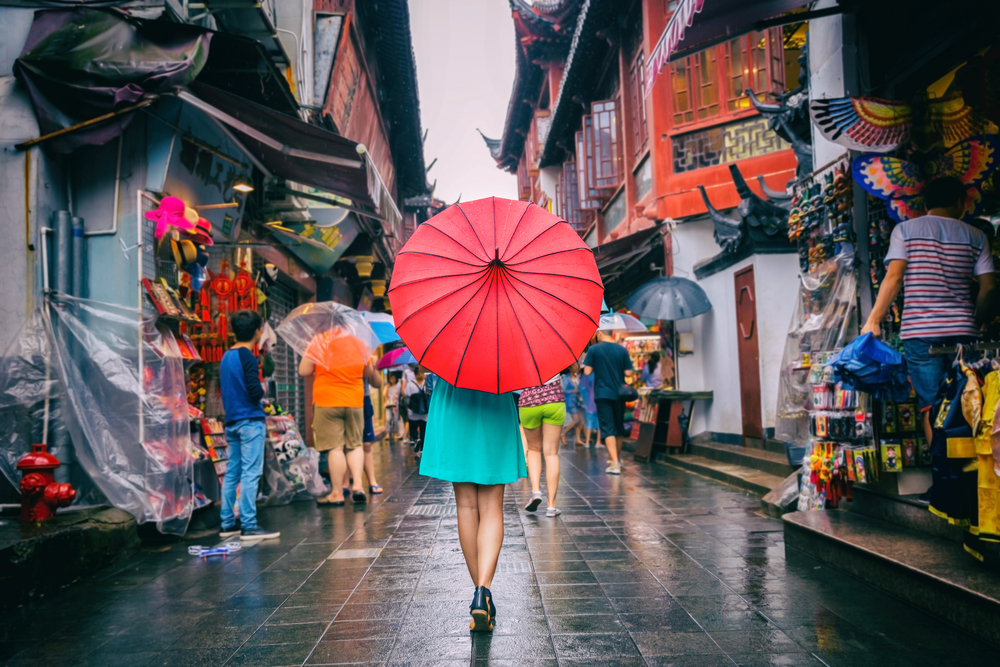 Woman walking with an umbrella on a rainy day in a market during the worst time to visit China