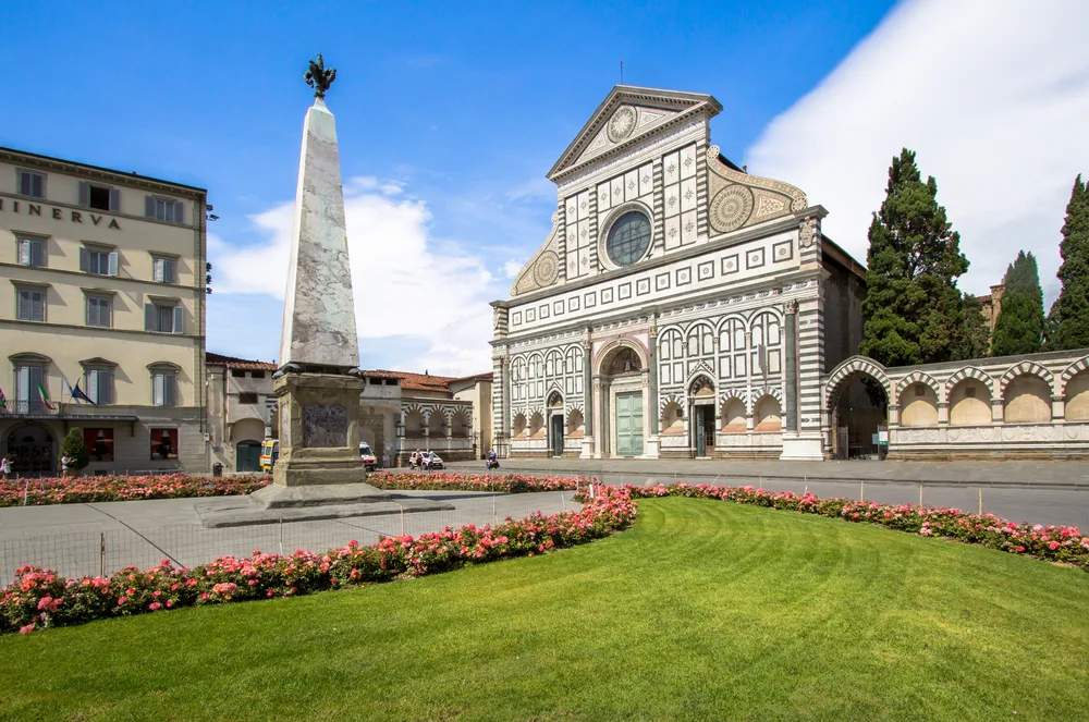 Santa Maria Novella, one of our top picks for where to stay in Florence, Italy, pictured from the front garden in front of the monument looking past the church into the blue sky