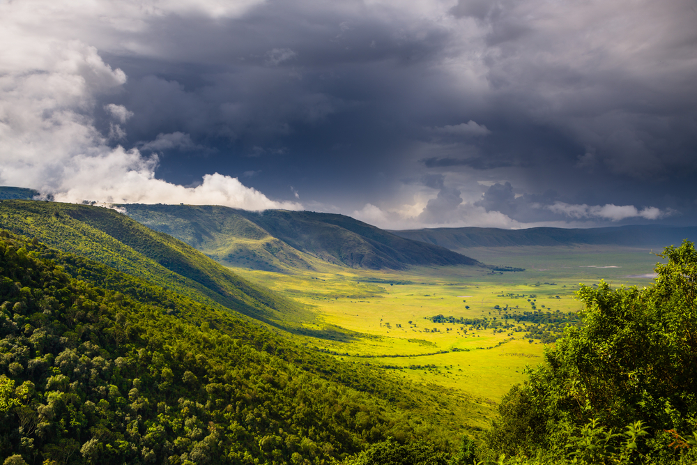 Rainforest spread out over the Ngorongoro Crater pictured with a black cloud over the expansive reserve during the rainy season, the overall cheapest time to visit Tanzania