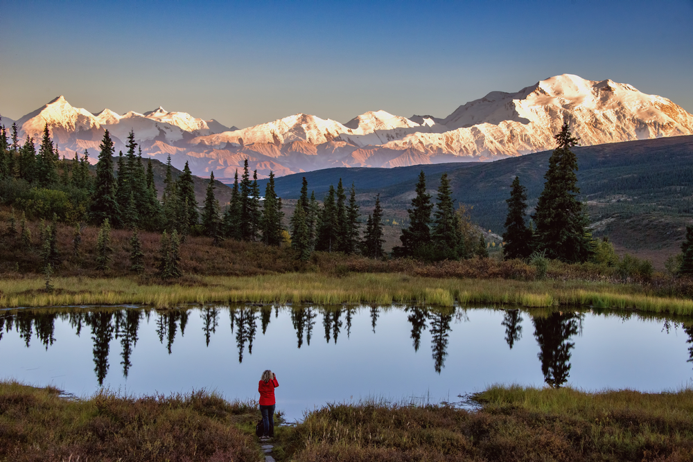 Beautiful view of Mount Denali at sunset over a tranquil pond for a piece on Is Alaska Safe