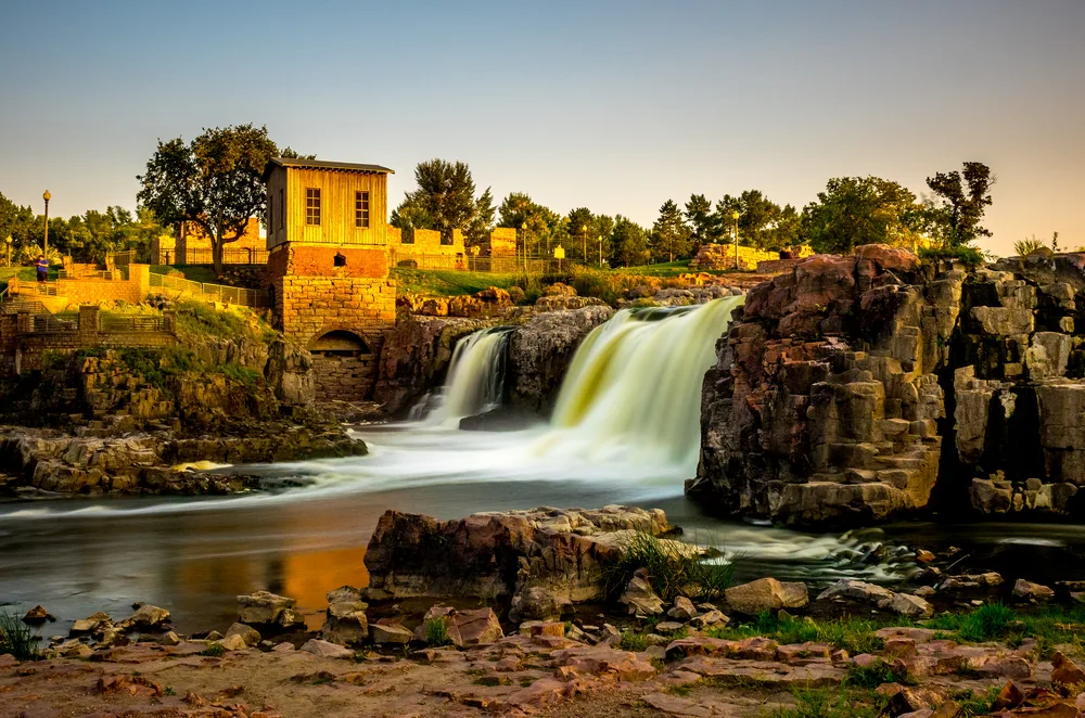 Sioux Falls pictured from the walking path with a gorgeous sunset over it for a piece on the best time to visit South Dakota