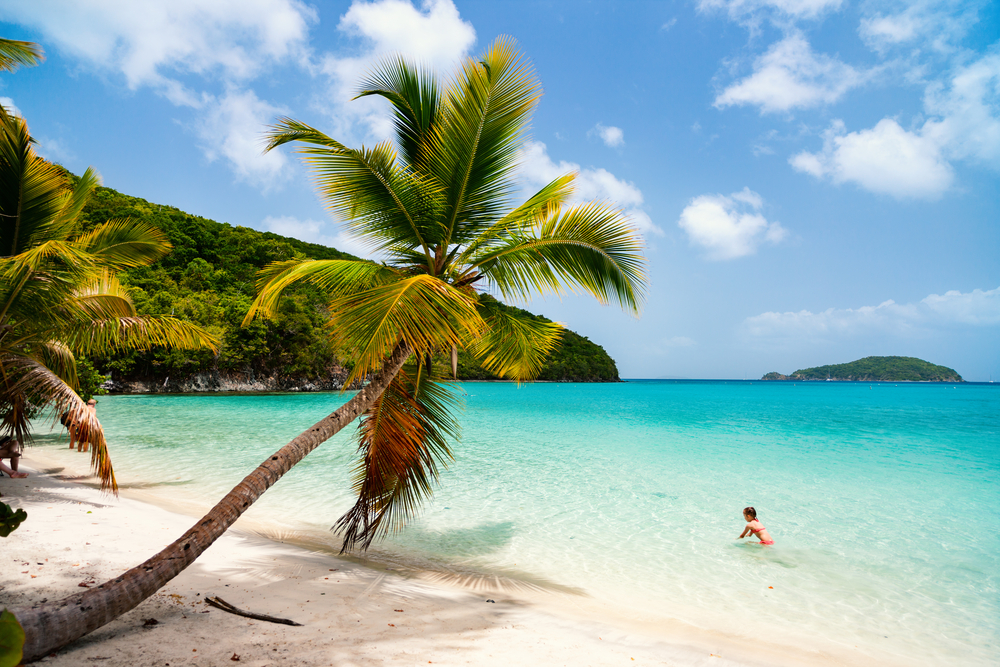 Gorgeous woman in a bikini swimming in turquoise waters in St. John against a blue sky during the best time to visit the US Virgin Islands