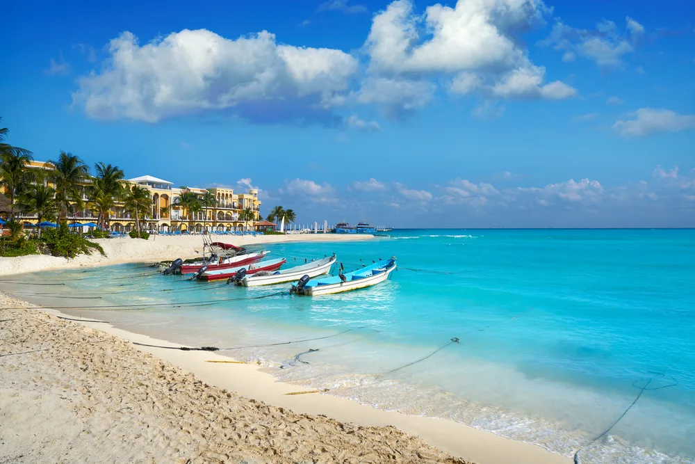 Boats on the white sand beaches of Playa Del Carmen during the best time to visit with blue skies in the background
