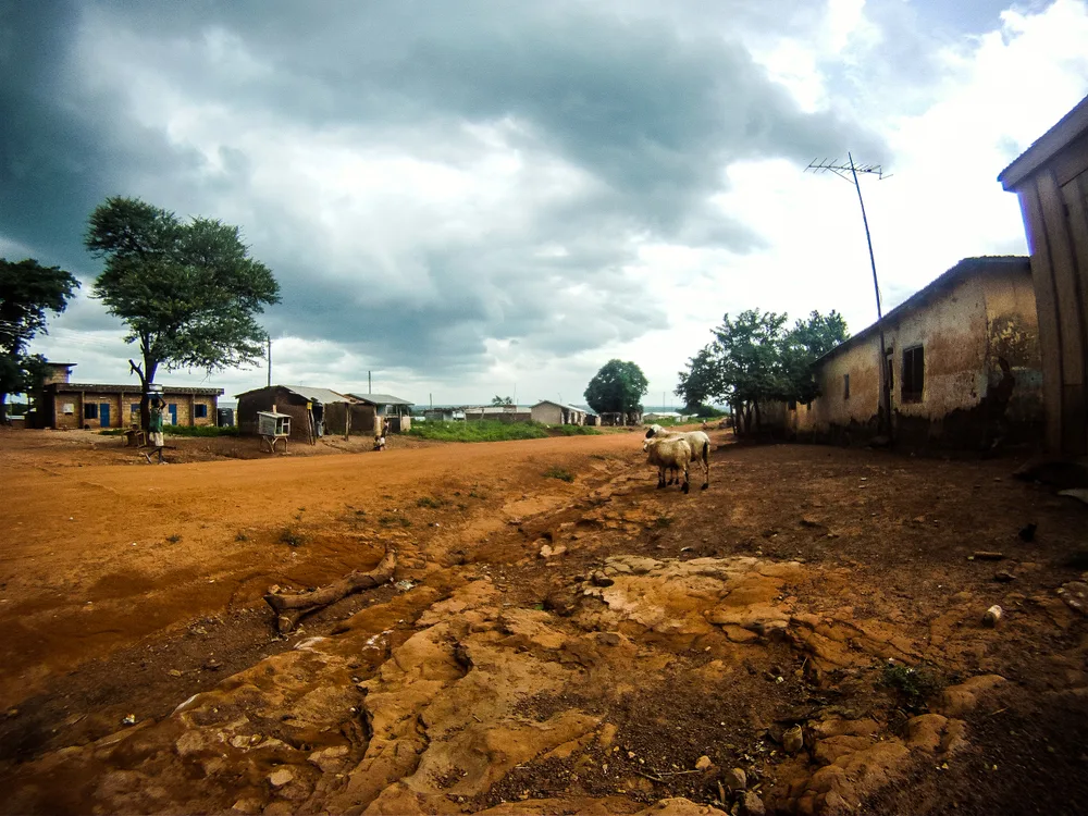 Rain clouds above a small town in Ghana, pictured during the worst time to visit, with goats on the dirt