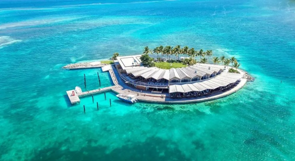 Aerial view of the above-water villas at Saba Rock Resort, one of the best resorts in the Virgin Islands, pictured with teal water surrounding it