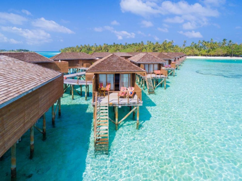 Huts above crystal clear teal water for a piece on the best resorts in the Maldives