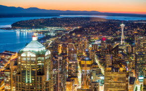As a featured image for the best day trips from Seattle an aerial view of the downtown skyline looking out toward the bay is seen on a clear day with an orange sky