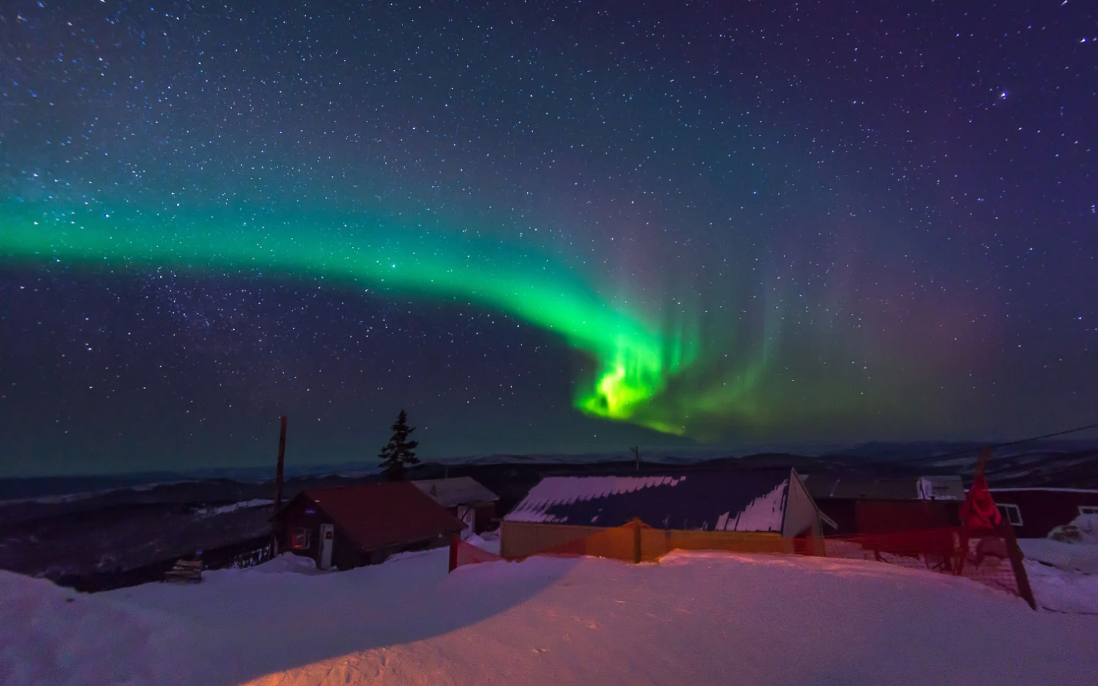 Gorgeous green sky of the northern lights over Fairbanks Alaska pictured during the best time to visit, with lots of stars in the sky